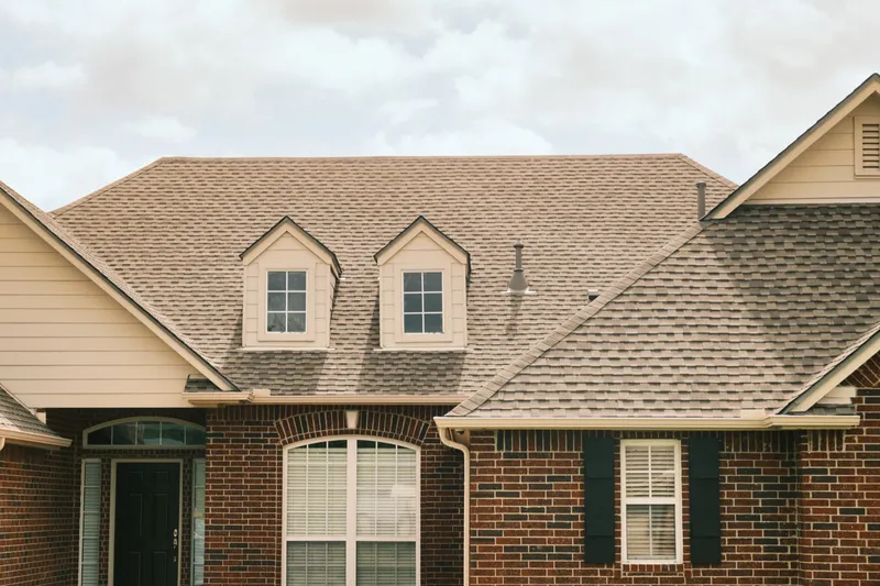 Twin dormers and a completed shingle roof on a brick home