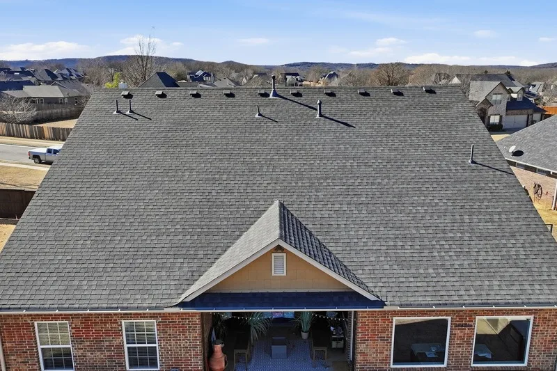 Completed shingle roof on a brick home with the Tulsa area hills behind it