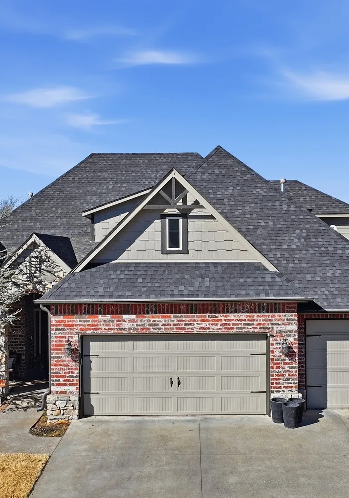 Finished shingle roof and gable peak above the garage of a brick home
